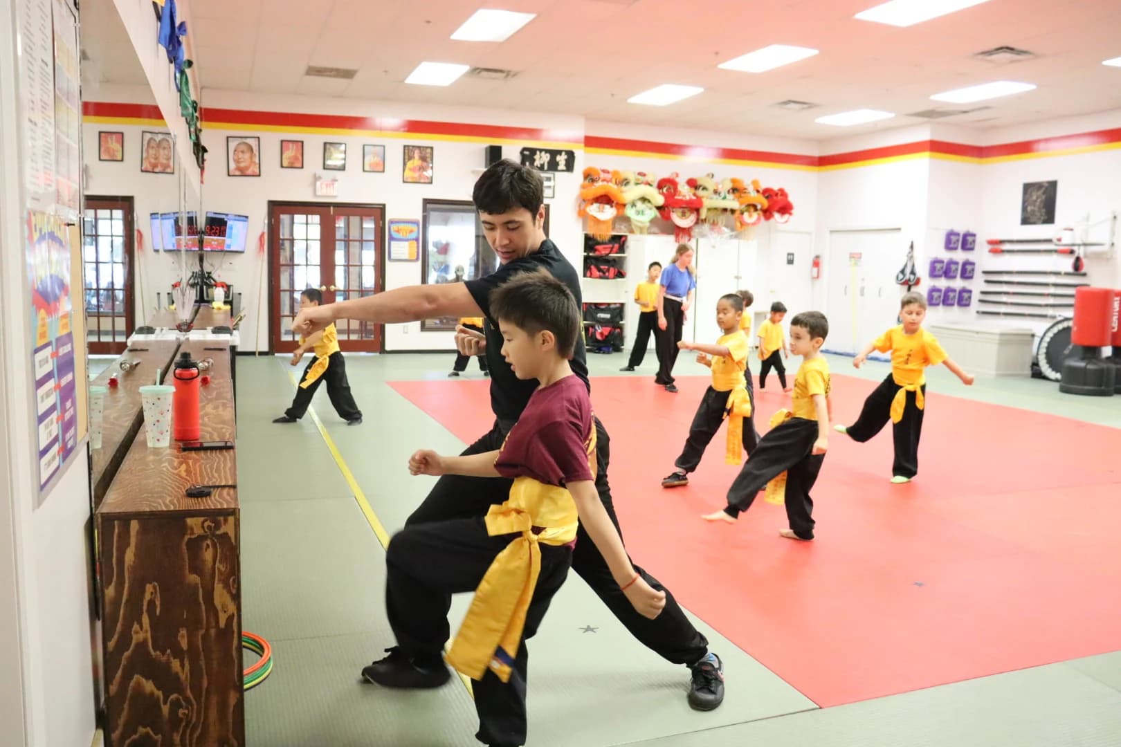 An instructor guiding a young student while classmates train behind