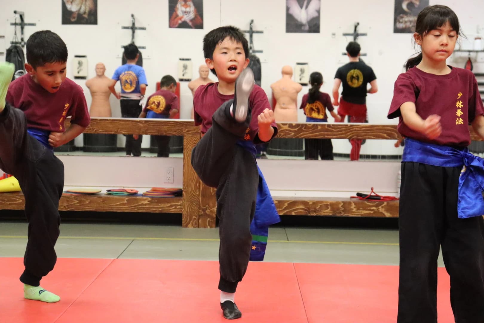 Young students throwing high kicks at pads during class