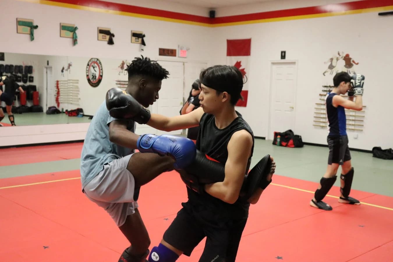 Two Sanda fighters clinching with gloves and headgear