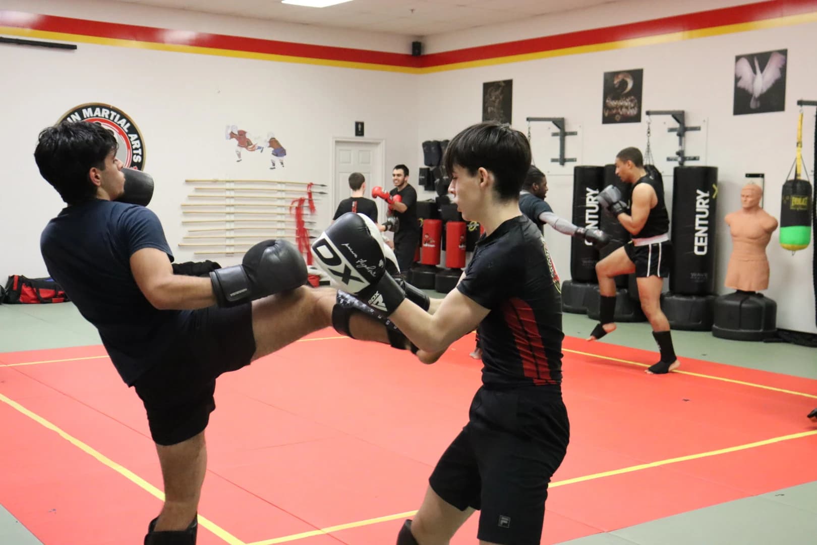Two Sanda students sparring with gloves on the red mats